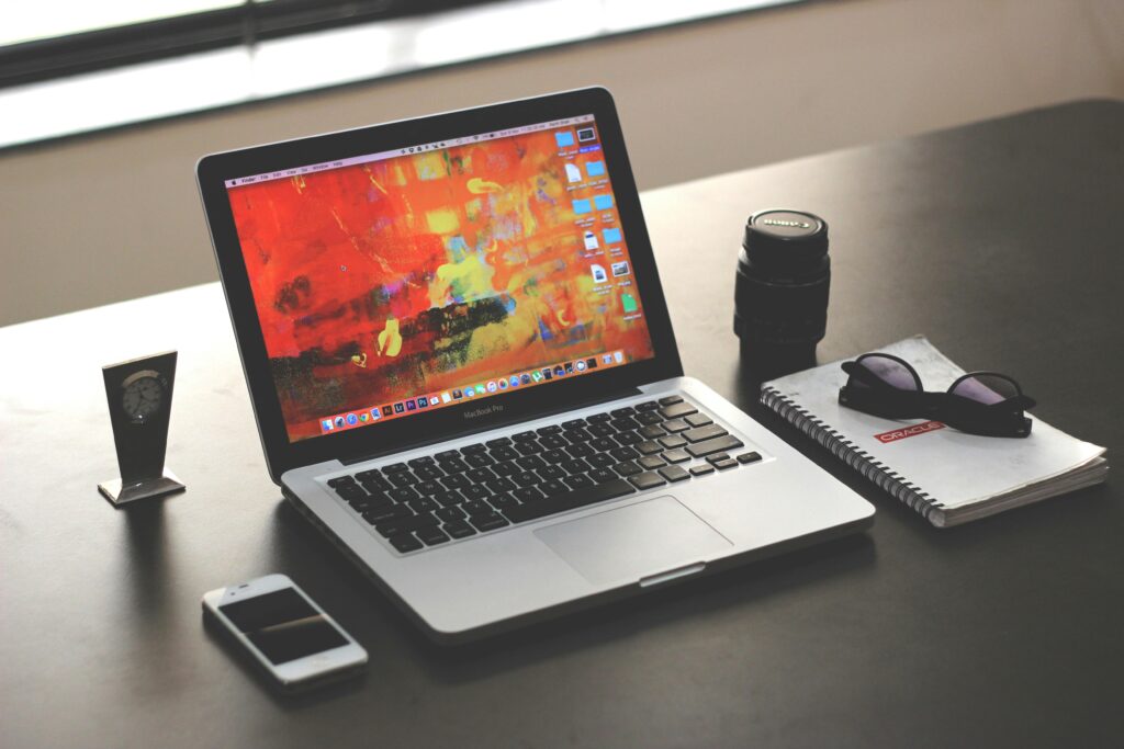 A clean, organized workspace featuring a MacBook, smartphone, and notebook.